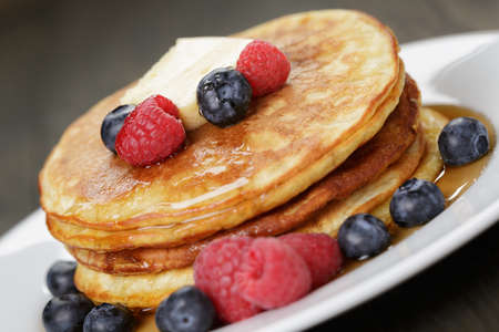 Pancakes with raspberry, blueberry and maple syrup, on oak wooden tableの写真素材