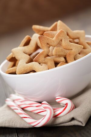 classic star cookies in white bowl with candy cane, on wood tableの写真素材