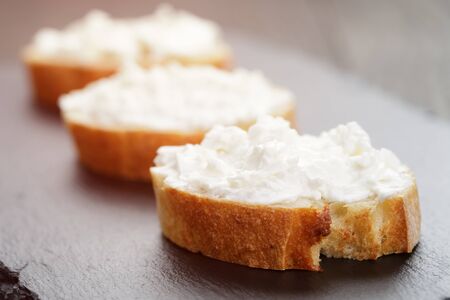 crunchy baguette slices with cream cheese on slate boardの写真素材
