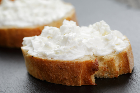 crunchy baguette slices with cream cheese on slate boardの写真素材