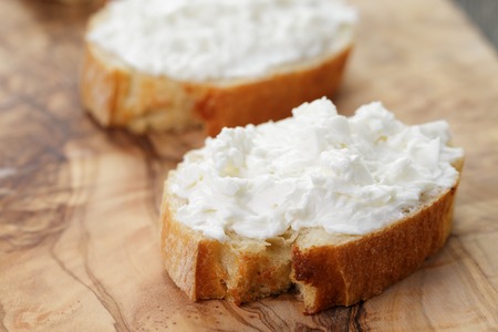 crunchy baguette slices with cream cheese on wood boardの写真素材