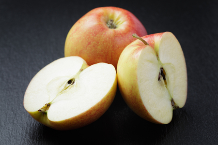 ripe apples sliced on slate board, close up photoの写真素材