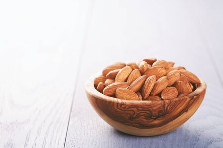 roasted almonds in wood bowl on blue wooden table, selective focusの写真素材
