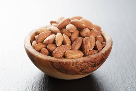 roasted almonds in wood bowl on slate board, selective focusの写真素材