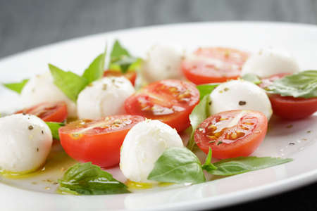 caprese salad with mini mozzarella balls and tomatoes, on old wood tableの写真素材