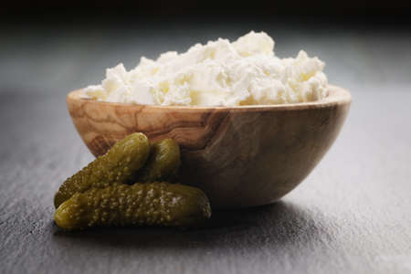 ricotta cheese in wooden bowl with marinate cucumbers on slate boardの写真素材