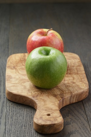 green and red apple on olive board, shallow focusの写真素材