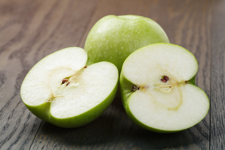 ripe green apples sliced on wood table, close up photoの写真素材