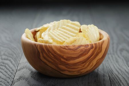 bowl full of salted potato ships on old wooden table, selective focusの写真素材