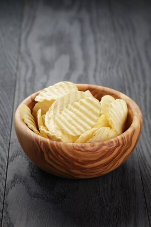 bowl full of salted potato ships on old wooden table, selective focusの写真素材