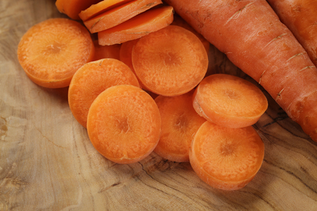 sliced organic carrot on olive wood cutting board, closeup photoの写真素材