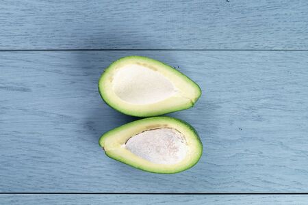 ripe green avocado on blue wood table, close up photo