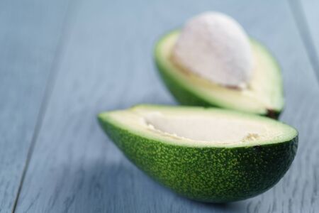 ripe green avocado on blue wood table, close up photo