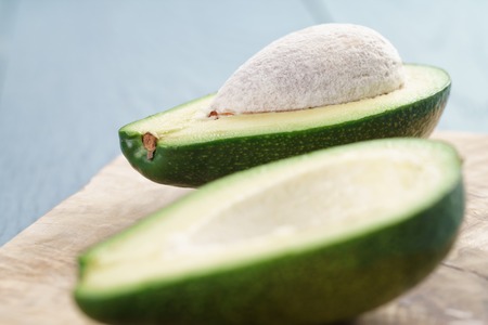 ripe green avocado on blue wood table, close up photo