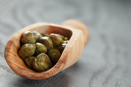 marinated capers in olive scoop on wood table, shallow focusの写真素材