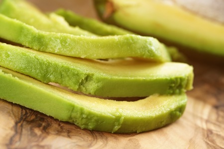 sliced ripe avocados on olive cutting board, shallow focusの写真素材