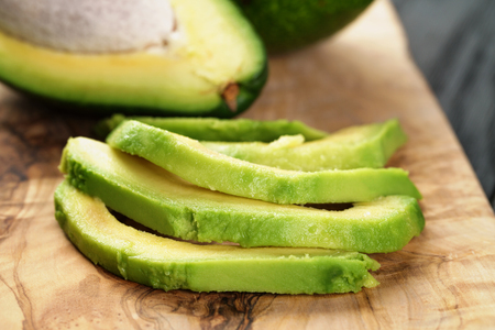 sliced ripe avocados on olive cutting board, shallow focusの写真素材