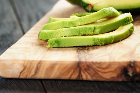 sliced ripe avocados on olive cutting board, shallow focusの写真素材