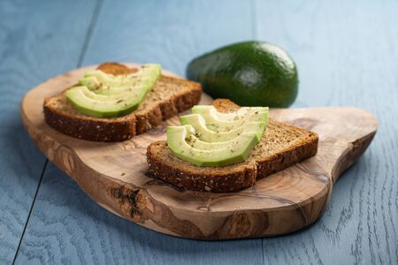 toasted rye bread with sliced avocado and herbs, simple rustic sandwichの写真素材