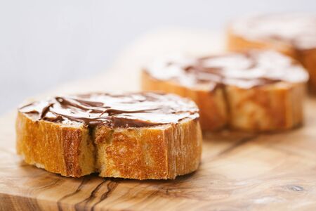 baguette slices with chocolate hazelnut spread on olive board, vintage tonedの写真素材