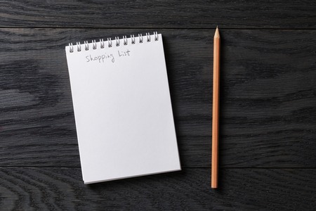 shopping list phrase in notepad on gray wood table, top viewの写真素材
