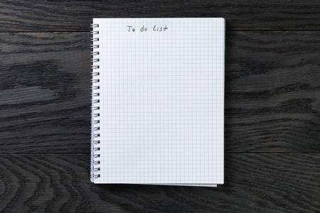 blank notepad with chequered pages on gray wood table with to do list phrase, top viewの写真素材