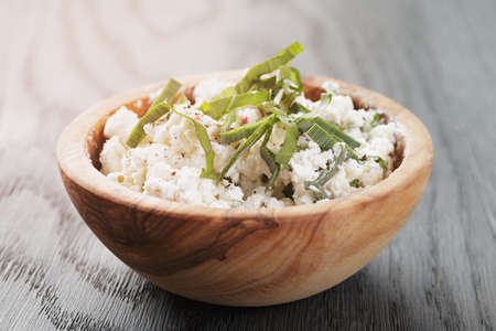 fresh ricotta with herbs in olive wood bowl on old tableの写真素材