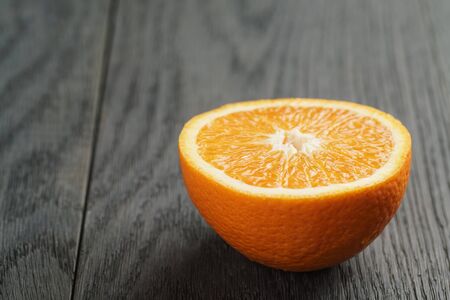 half of ripe orange on wooden table, shallow focusの写真素材