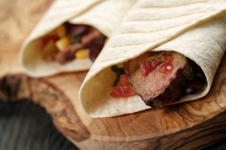 closeup photo of fresh homemade burritos with beef on wood board, shallow dofの写真素材