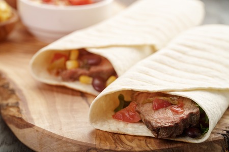 closeup photo of fresh homemade burritos with beef on wood board, shallow dofの写真素材