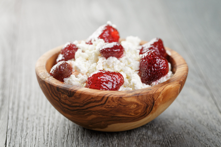 cottage cheese with preserved strawberry in wood bowl on oak table, selective focusの写真素材