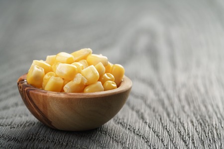 sweet canned corn in wood bowl on wood table, selective focusの写真素材