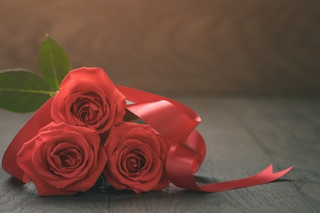 three red roses on wooden table, shallow focusの写真素材