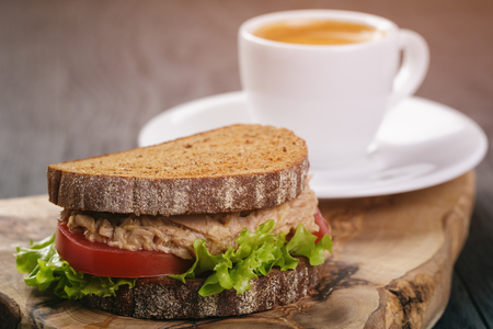 rye bread sandwich with tuna and coffee on wood backgroundの写真素材