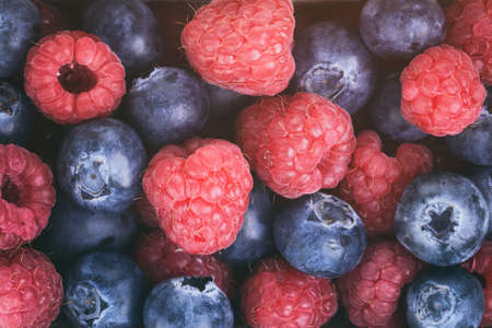 fresh raspberries and blueberries top view background, vintage tonedの写真素材