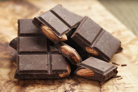 homemade dark chocolate with almond nuts on wooden board, shallow focus