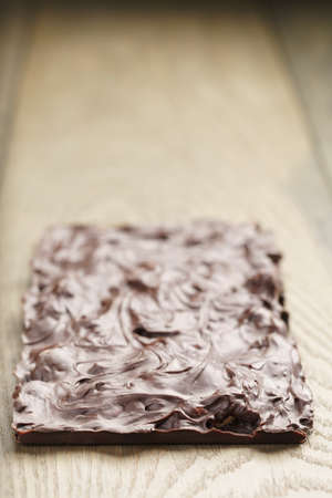 whole homemade bar of chocolate with cashew nuts reverse side, on wooden board shalow focusの写真素材