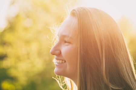 pretty teen girl smiling in warm sunset, shallow focusの写真素材