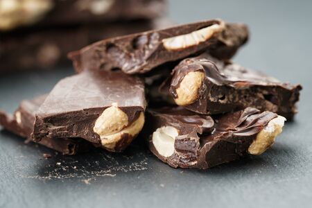 broken homemade bar of chocolate with cashew nuts reverse side, on slate board shalow focusの写真素材