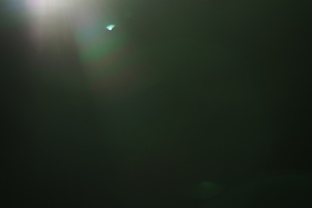 real green lens flare over dark background, for overlayの写真素材