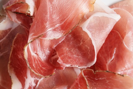 speck slices on white plate on old wood table, shallow focusの写真素材