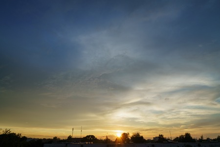 sunset clouds and colored sky over town, silhouette roofs