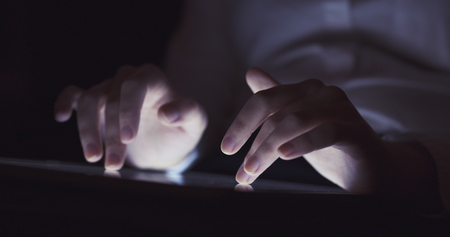 young female teen using tablet pc in the dark environment very shallow focusの写真素材