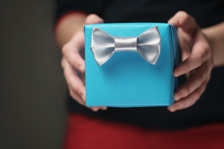 female teen hands show blue paper gift box with gentleman bow, shallow focusの写真素材