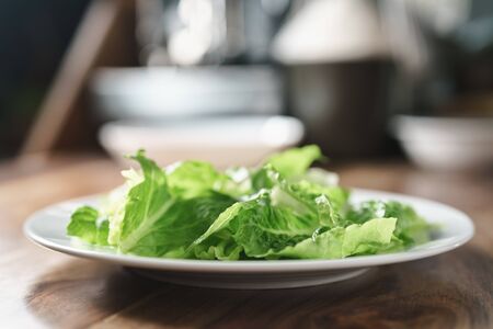 torn romaine lettuce leaves in plate on wood table, diet foodの写真素材