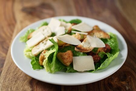 caesar salad with chicken on old wooden table, shallow focusの写真素材