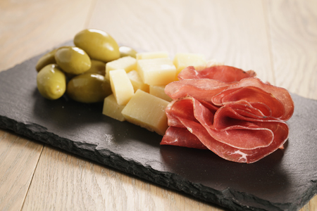 bresaola with parmesan cheese and olives on slate board, italian antipastiの写真素材