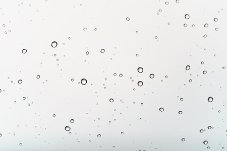 clean round water drops on transparent glass, closeup background photoの写真素材