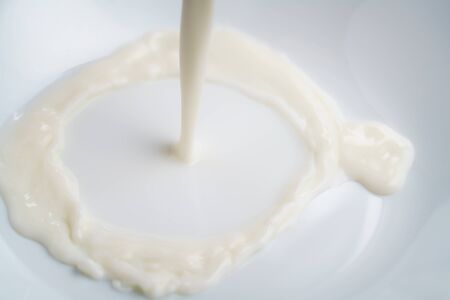 pouring milk into bowl from above, closeup photo