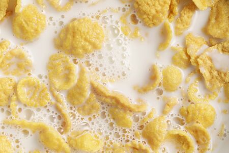 closeup of corn flakes with milk in bowl directly above, healthy food background